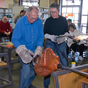 two people are blowing glass in classroom