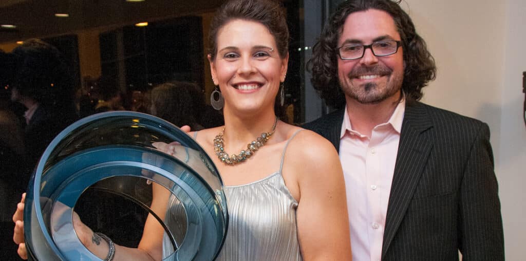 two people holding glass art piece