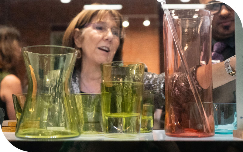 Shopper selecting Penn/Fairmount glassware in the Shop